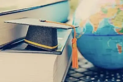 小小的纸质毕业帽放在书本上，旁边是塑料地球仪